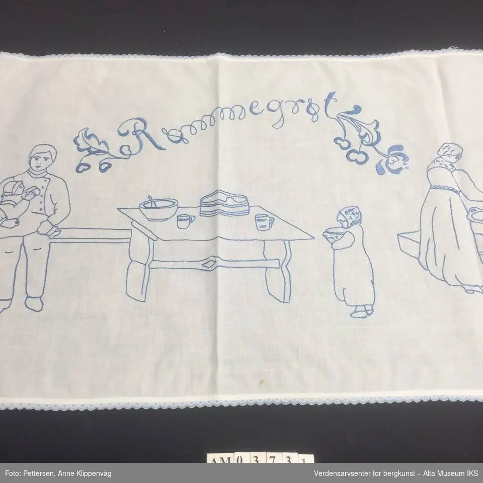 Rektangulært, hvit bordløper. Brodert motiv med blå tråd: Kjøkkeninteriør med tre personer.