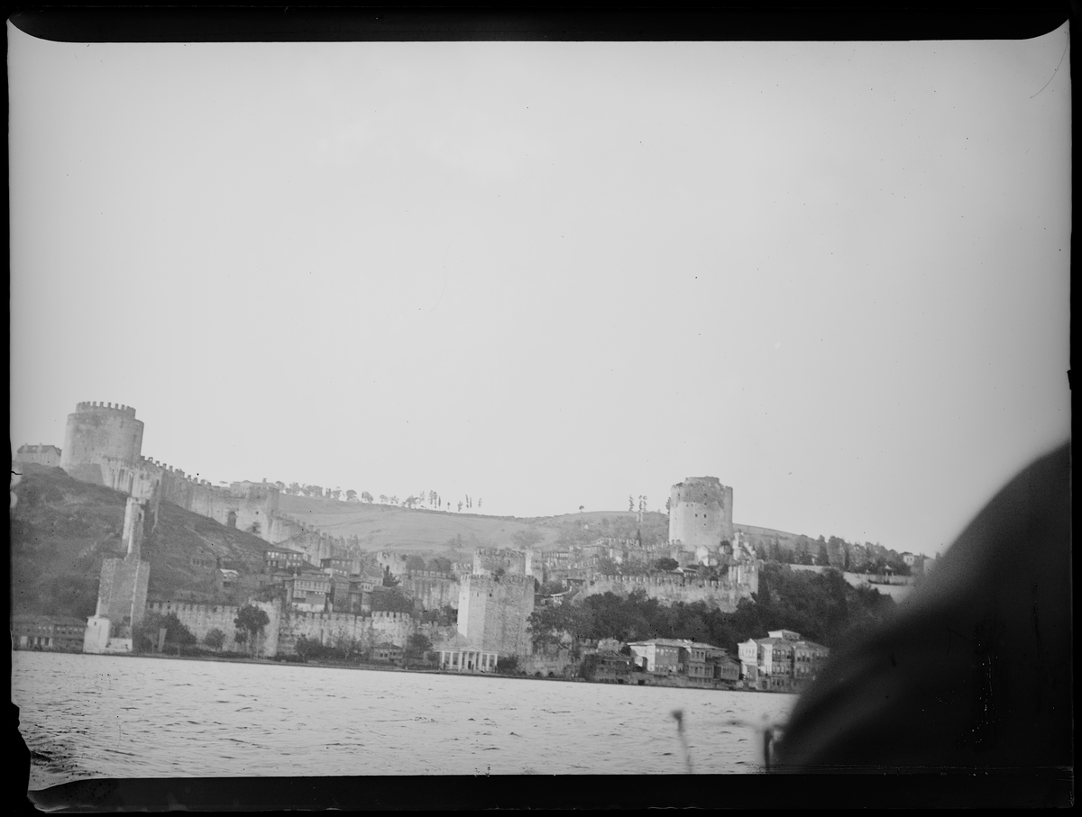 "Jerusalem 10, Cairo 6" (inskr eske). Alanya. Festninger og mur, med bebyggelse rundt. Bilde tatt fra båt.