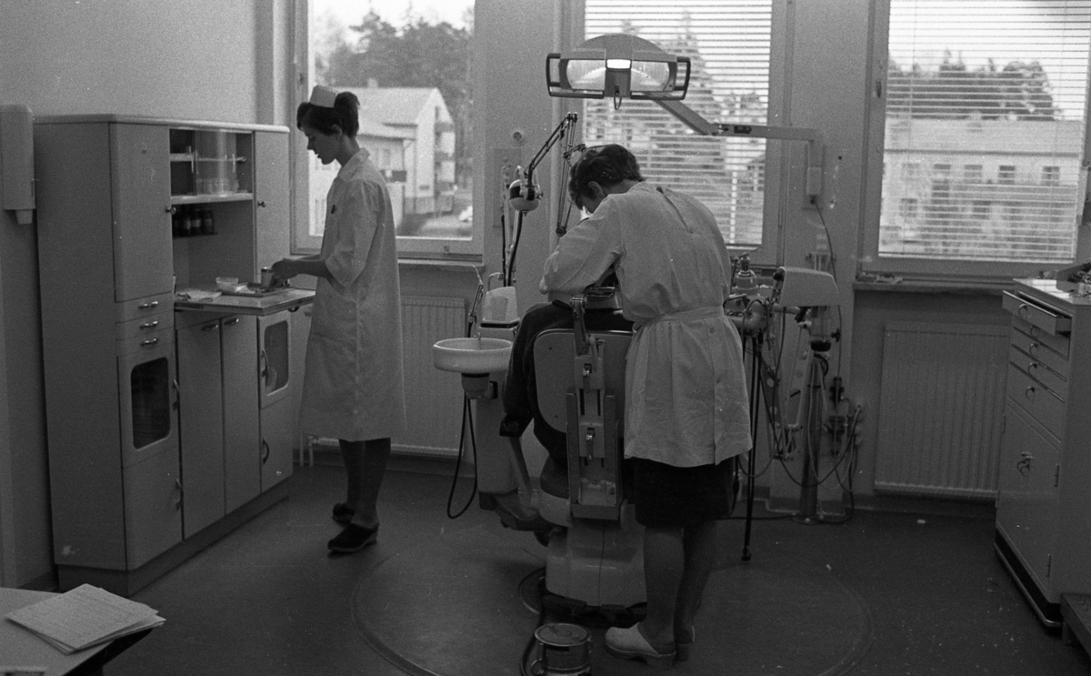 Fellingsbro tandklinik 8 april 1968

Tandläkare gör tandvård på en patient. Tandsköterskan
står vid ett skåp och arbetar vid ett fällbart bord.