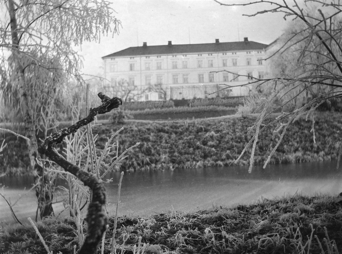 Hovedbygningen på Linderud Gård sett fra nederst i hagen, ved dammen. Trær og planter er dekket av rim.