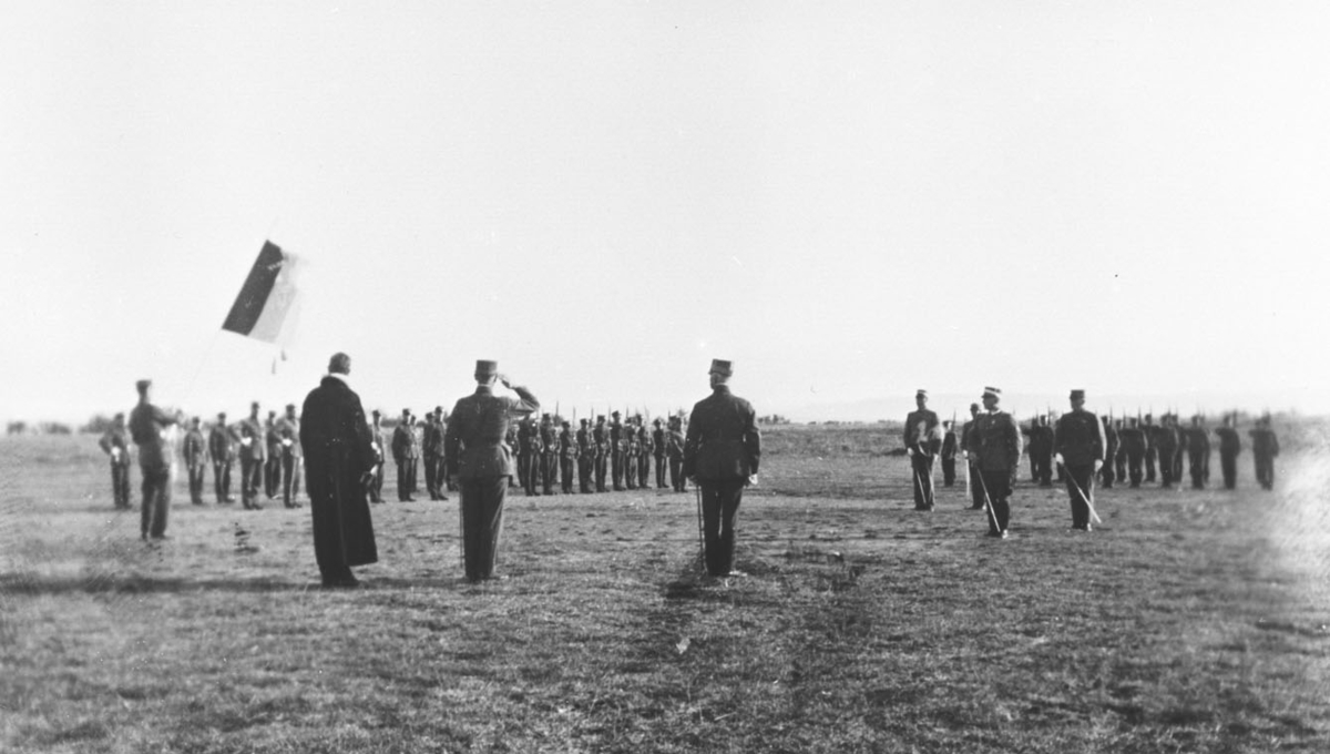 Vi antar at bildene er tatt i forbindelse med gjenopprettelse av Varanger batlajon 01.07.1934. Bildet viser oppstillinging av soldater på eksersersplassen på Nybergmoen 1934. I forgrunnen Prost Skauge, General Johansen og hans adjuntant, alle med ryggen mot kamera.