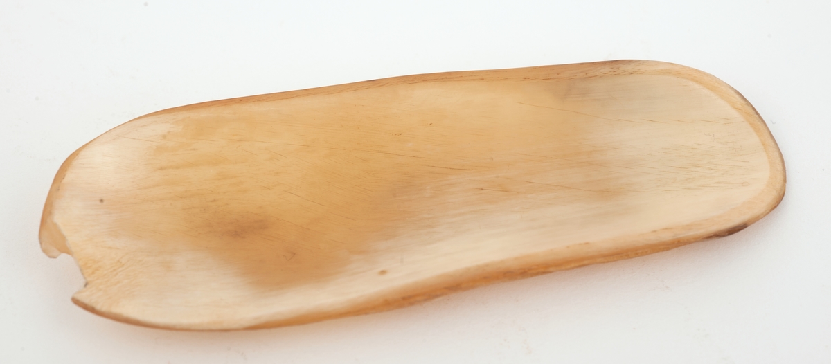 En båtlignende form av horn med den ene enden noe smalere og flatere for lettere å kunne dyttes inn i en papirkapsel.
Lysebrun, litt melert.