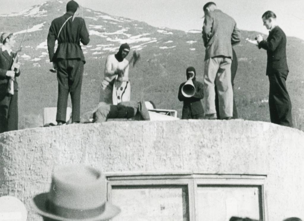 Bildet viser halshugging av Hitler. Mannen med gevær heter Odd Benjaminsen. Mannen med øksa heter Kristen Bakkejord. Helt til høyre står fotograf Karl Knudsen. Det var "Russen 1945" som arrangerte forestillingen.