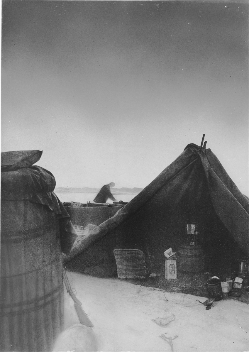 Lägret vid "Örnens" landningsplats. Till vänster gondolen, till höger tältet. Mellan dem skymtar båten. I tältet ses proviant och kokkärl. I mitten kokapparat och till vänster en proviantkorg. Framtagning av bilderna gjordes av docent John Hertzberg år 1930 på Fotografi, Tekniska Högskolan.
