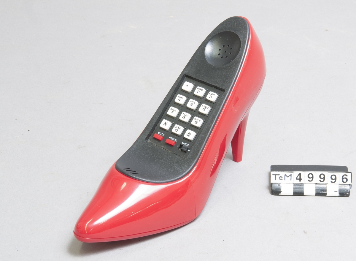 Telefon med inställningsmöjlighet för tonval eller impulsval, mute, återuppringning av senast slagna nummer. Modell efter damsko (pumps), i originalkartong.