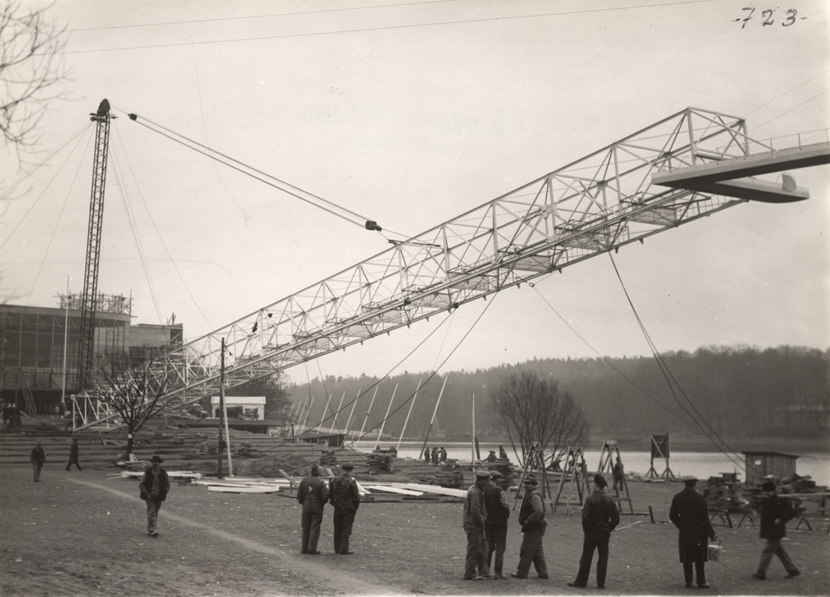 Aktiebolaget Bröderna Hedlund. Reklammasten för Stockholms-utställningen under resning den 19 jan 1930. Masten, vars tvärsektion var 3 x 3 m och c:a 80 m hög, vikt c:a 30 ton, restes på ungefär 3 timmar.