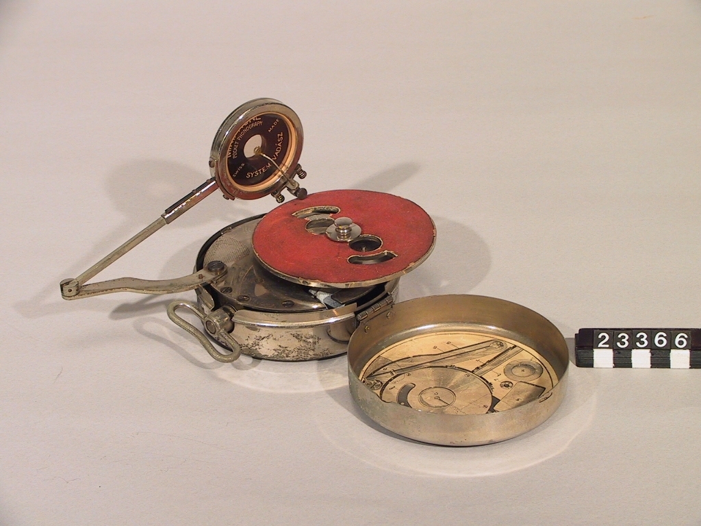 Fickgrammofon, helt i metall, hopfällbar, patenterat system. Text på locket: "Pocket Phonograph Mikiphone System VadÃ¡sz Patented in all countries". "Ljudförstärkare" ( hopvikbar tratt) saknas dock.