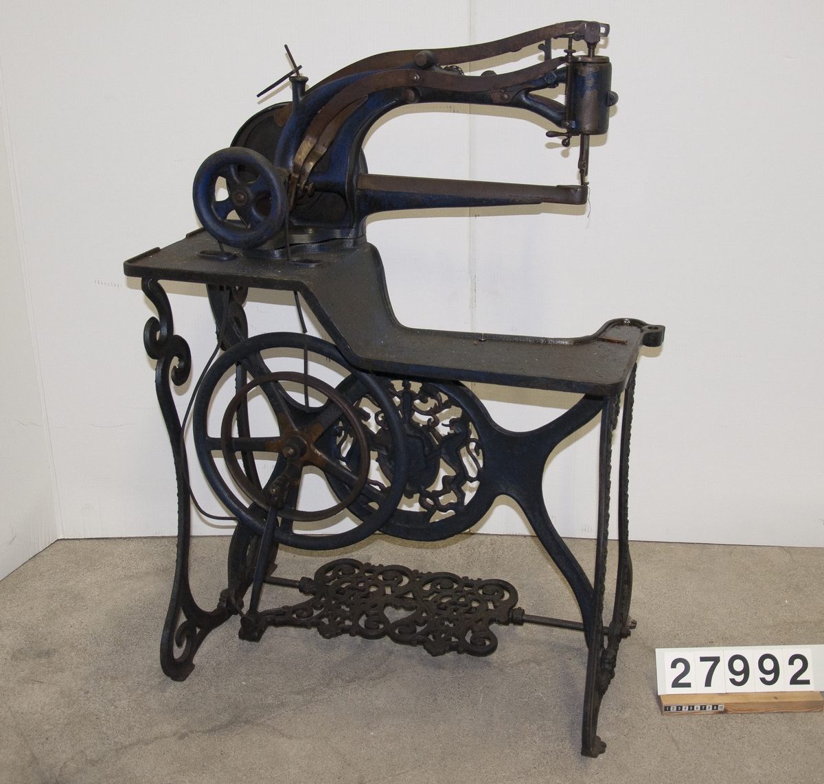 Symaskin, "Patent Elastique" för skonåtling, hand- och trampdriven, på stativ av järn.