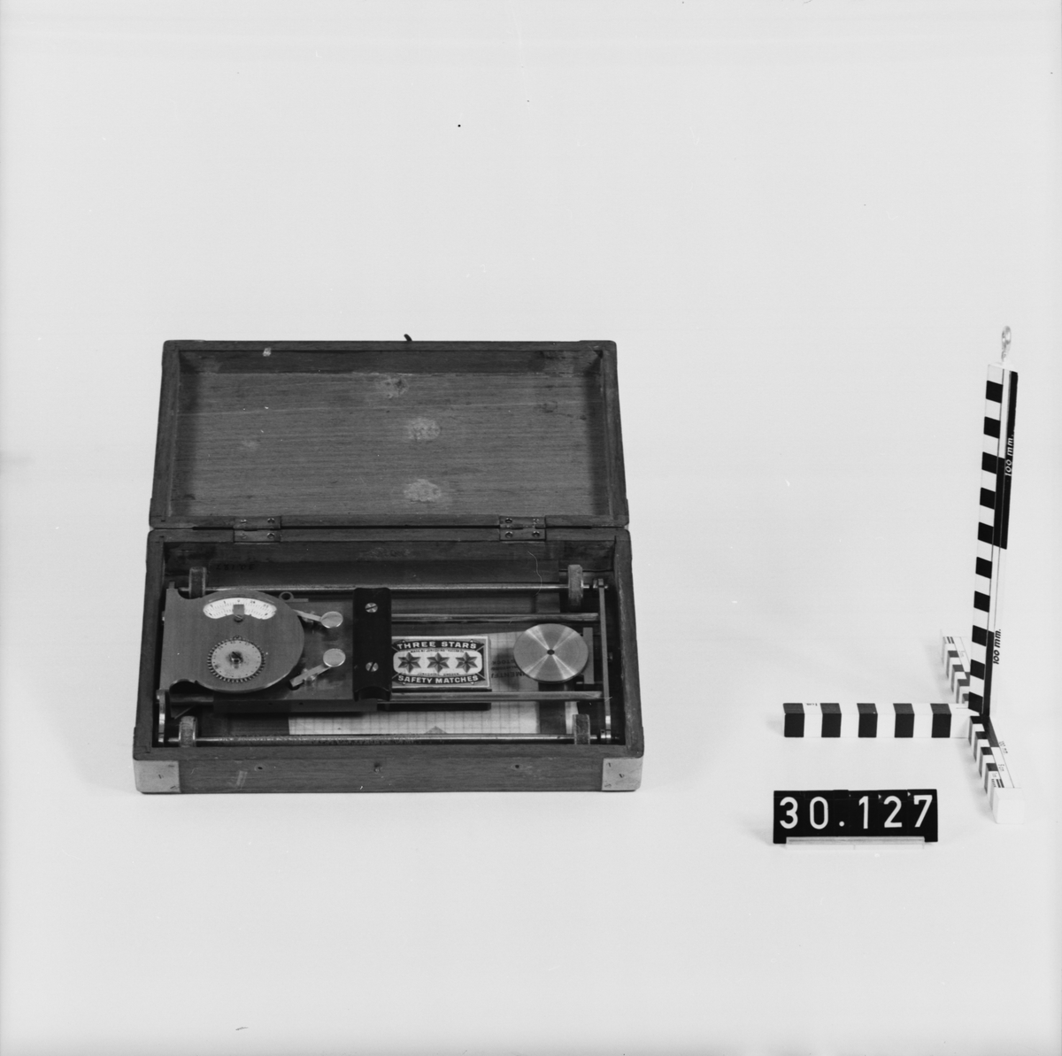 Rullplanimeter av mässing, järn och glas. Förvarad i etui av trä innehållande instrument med graderad skiva, rektangulär polett av glas i mässingsram samt påse med glimmerskivor. Lådans längd: 265 mm, bredd: 165 mm, höjd: 54 mm, total vikt: 1.7 kg. Rostig.