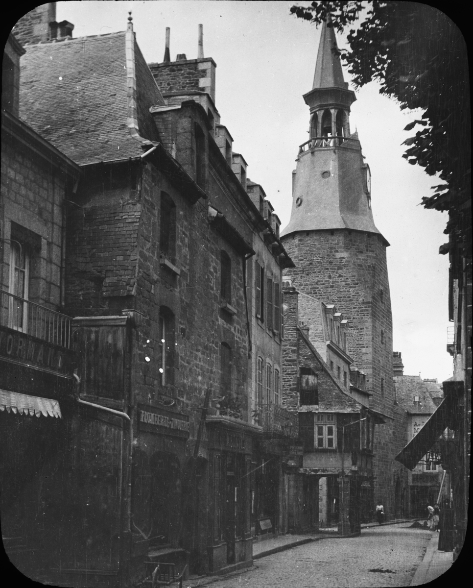Skioptikonbild med motiv av tornet Tour de l'Horloge i Dinan, sett från Rue de l'Horloge.

Bilden har förvarats i kartong märkt: Resan 1908. Dinan 7. XV