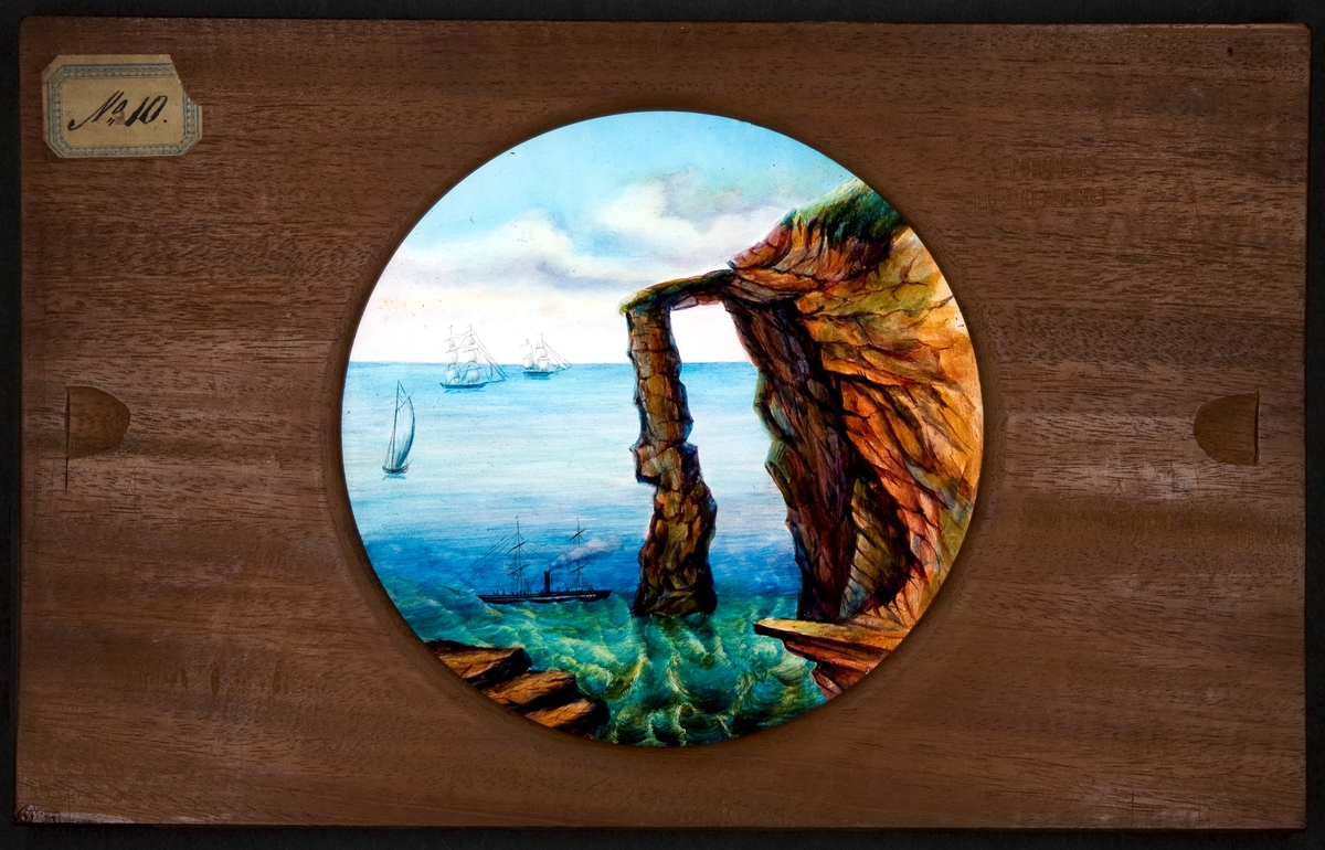 Laterna magica bild målad i färg på glasskiva.
"Hvalfbåge af lava på kusten ....arhelen af Slappen på Island".