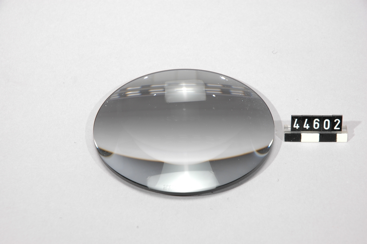 En optiskt slipad rund plankonvex glaslins som metalliserats på den plana sidan. Vilket gör glaslinsen till en förstorande spegel från det konvexa hållet. Den plana ytan är täckt med svart filt som går att fästa på medföljande klisterlappar med kardborreyta.  Spegellinsen levereras i genomskinlig kvadratisk plastask med grå tygpåse av mikrofiber och tre kardborrelappar som tillbehör.  Märkning: SPEGELZOOM Â® by awum