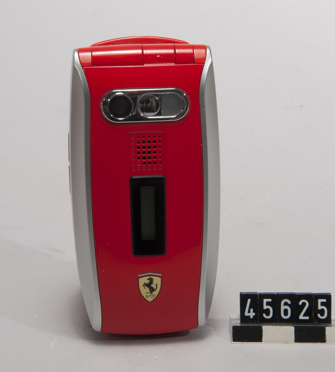 GSM mobiltelefon 900/1800/1900 GPRS, Sharp Corp typ GX25 Ferrari Edition. Röd, med bilmärket Ferraris logotyp. Obegagnad i originalkartong, med laddare, handsfree, handbok och CD-skiva. Operatörslåst till Vodafone Sveriges SIM-kort.
Tillbehör: Laddare, handsfree, CD-skiva med drivrutiner/programvara, batteri.