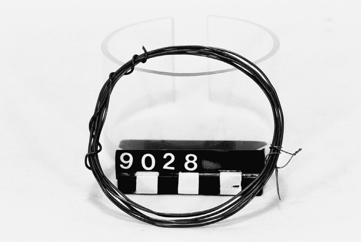 Ett stycke dragen (?) mässingstråd, i ring. Diameter: c.a. 1.3 mm, längd: c.a. 1.8 m.