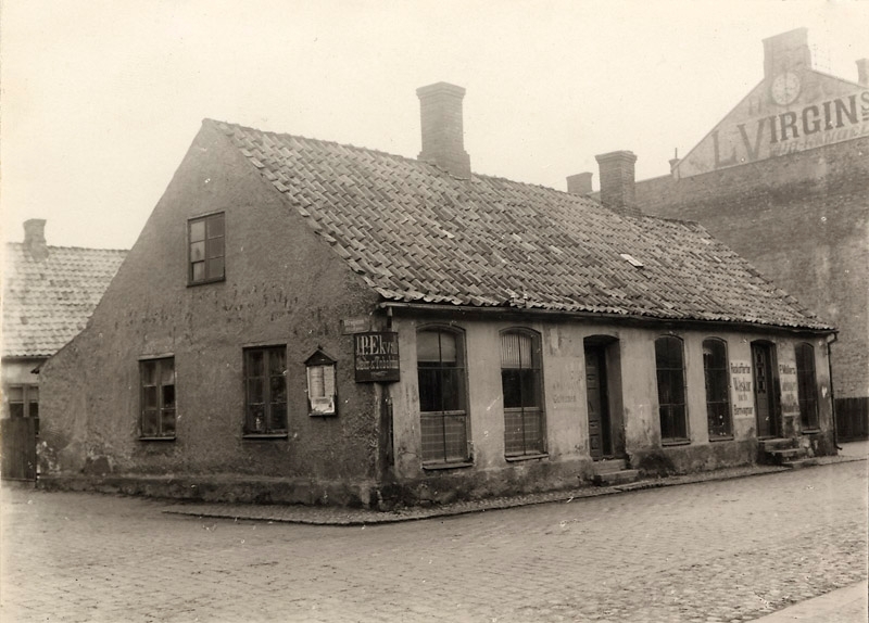 Hus vid Algatan-Brogatan 1890, J P Ekvalls cigarr och tobaksaffär, P Möllers reskoffertar väskor och barnvagnar, L Virgins.