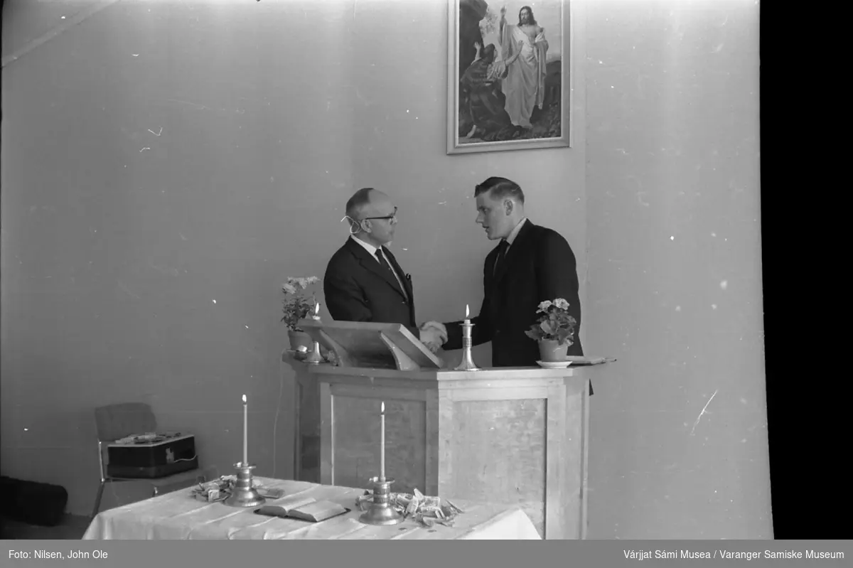 Innvielse av ungdomssenteret i Vestre Jakobselv. Steinar Harila står til høyre på tale / prekestolen og håndhilser på en mann i sort dress. På stolen til venstre ligger en båndopptaker. 19. juni 1966.