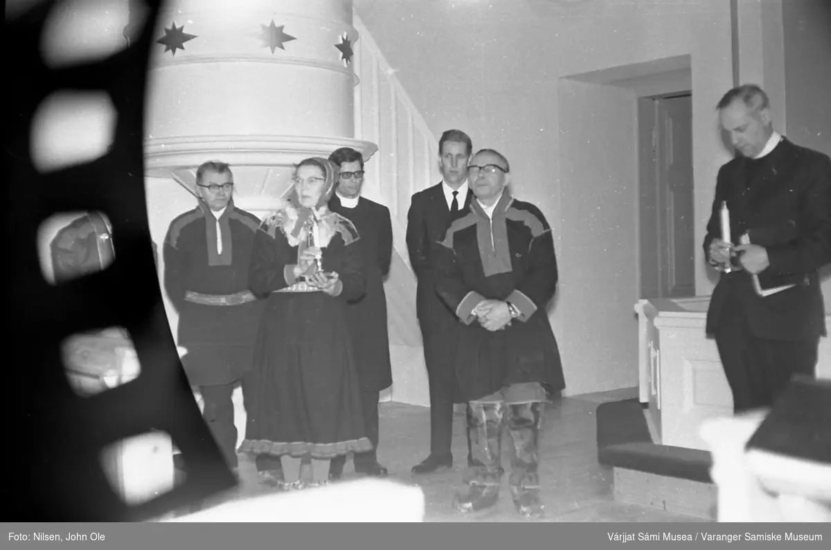 Gruppebilde inne i en kirke. Kvinnen i kofte er Signe Nilsen og presten er Erik Schytte Blix. Ukjent sted høsten 1966.