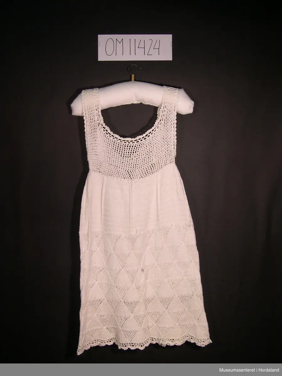 Form: skrådd kjole med breie, hekla skulderband og  mønsterstrikk
