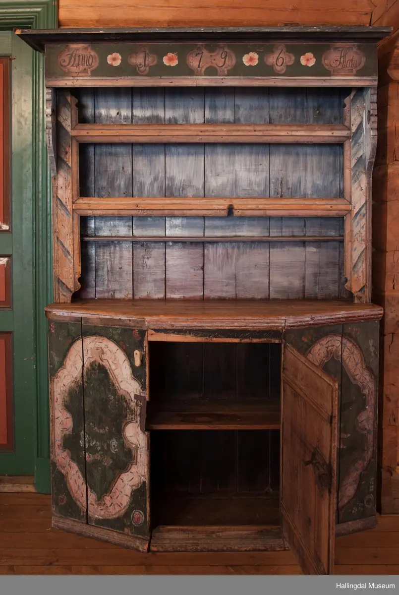Marmorert toppstykke over felt med fem fyllinger.  Feltet grønnmalt med røde og hvite blomster.  Fyllingene, hvit bunn, sortmalte bokstaver og tall:  Anno 1796 H. Sata.  Overskapet har to hyller med lister og en smal hylle med profilert kant.  Bakveggen hvitmalt med rester etter mørkere undermaling, sideveggene marmorert.  Underskapet tredelt, fremspingende midtparti som er dør.  Fyllinger på de tre delene.  Grønn bunnfarge.  Slitt rosemaling, hvitt og rosa.  Profilert gulvlist.  Nøkkelhull med beslag og defekt lås av jern.  En hylle innvendig.