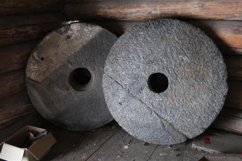 Bilde av kvennsteinene som står lagret opp mot tømmerveggen i kvenna.
