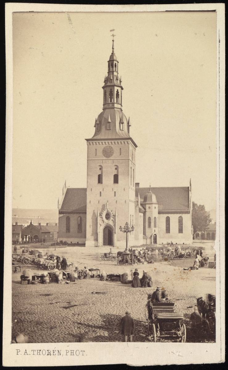 Bilde av Oslo Domkirke sett fra Stortorget, som er fullt av folk og salgsvogner.
