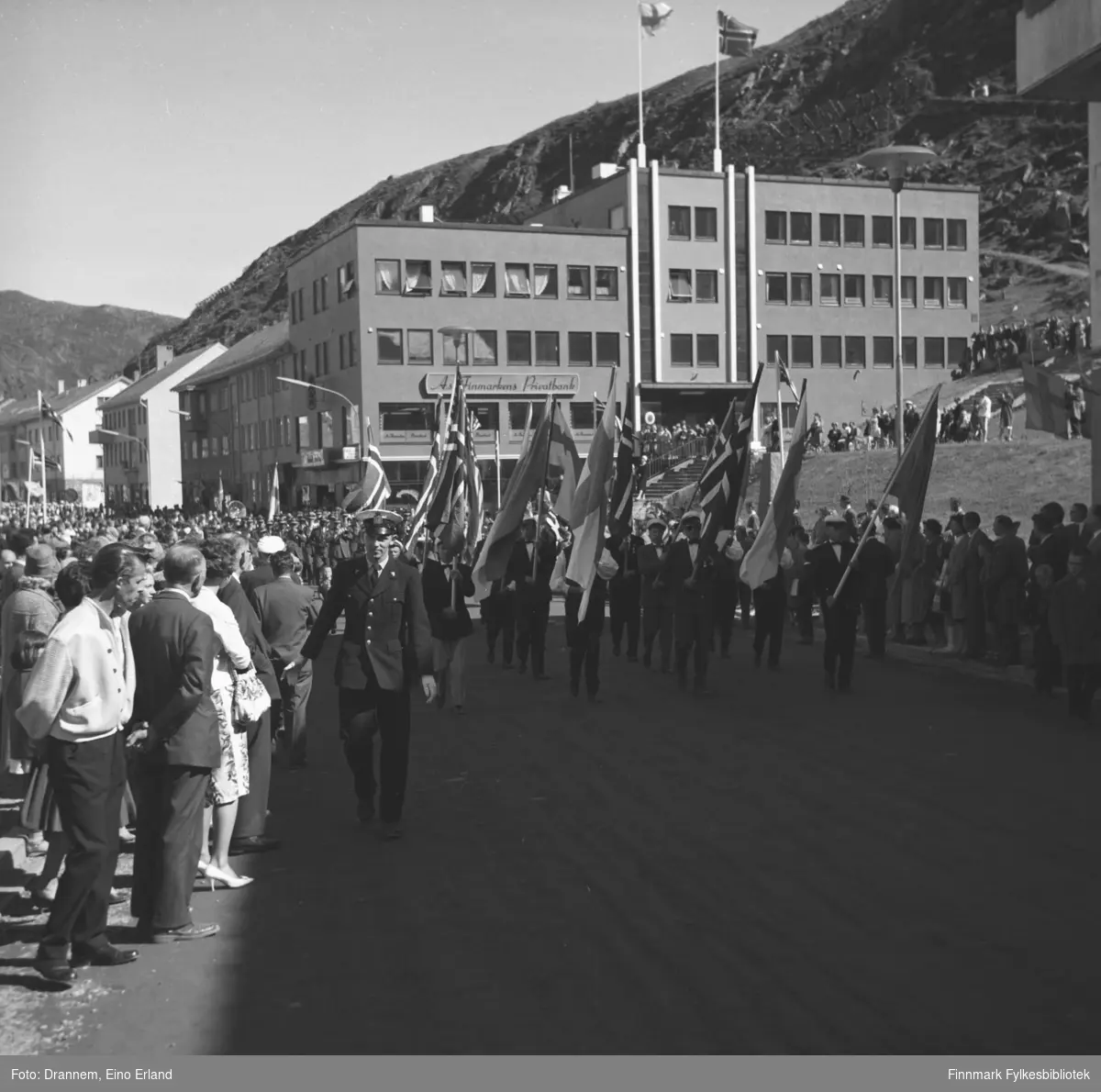 Et opptog går gjennom Strandgata med norske og finske flagg og en stor folkemengde står langs veien og ser på. Motivet kan være fra den norsk-finske foreningens store arrangement sommeren 1961.