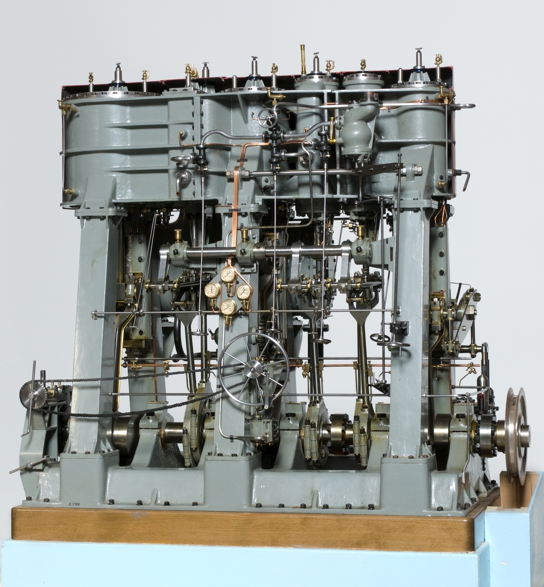 Modell av trippelexpansionsmaskin från lastfartyget SONJA byggd på Helsingborgs varv 1940. Komplett till alla delar, monterad på polerad träplatta. gråmålat stativ, cylindrarnas skyddskåpa avlägsnad på manöversidan. Cylindrarnas kannor ej insatta. Tillhörande elmotor för kilremsdrift.