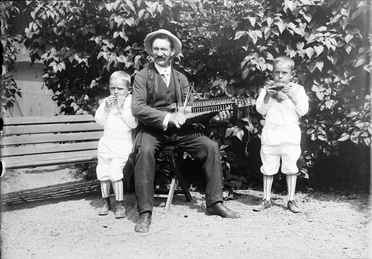 Handlande Emil A. Sjulander spelande nyckelharpa tillsammans med två av sina söner, Östhammar, Uppland