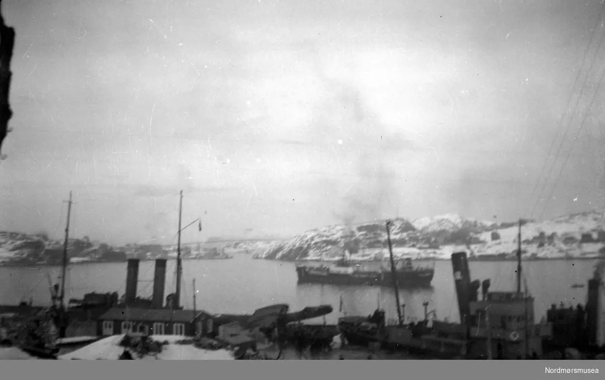 Skip på havna og ved kai på Kirkelandet i Kristiansund. Vi ser Nordlandet til høyre og Gomalandet til venstre i bildet. Bildet er tatt etter bombinga 1940. Fra Nordmøre museums fotosamlinger.
