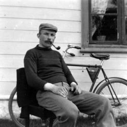 Foto av Georg Sverdrup, her sittende på en hagebenk og røyke