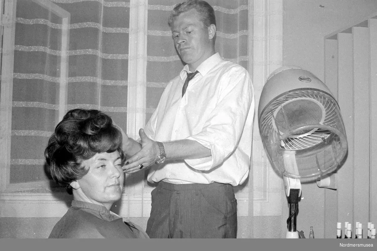 Fotoserie med hårmoter fra tiden omkring 1969. Her ser vi en kvinne i frisørstolen mens frisøren arbeider med sveisen. Repotasjebilde fra Romsdalspostens arkiv. Fra Nordmøre Museums fotosamlinger.
