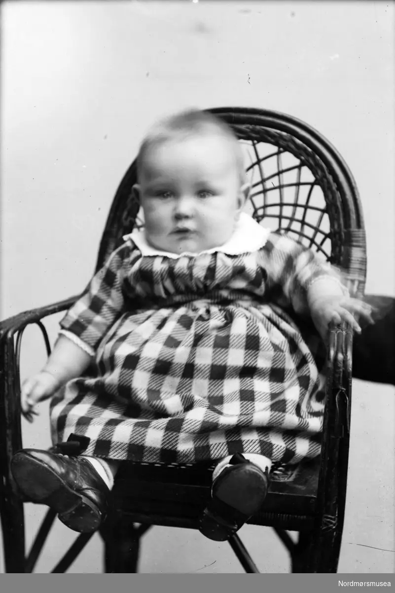 Portrett av et spedbarn sittende i en stol. Muligens fra Sverdrupfamilien/slekten, eventuelt fra deres bekjentskaper. Datering er ukjent, men trolig omkring 1920 til 1930. Fra Nordmøre museums fotosamlinger. EFR2015