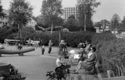 Foto fra parken med lekeplassen i forgrunnen, samt
 Kirkelan