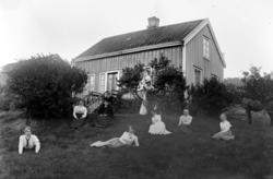 Foto av 8 kvinner sittende spredt på en plen foran et mindre