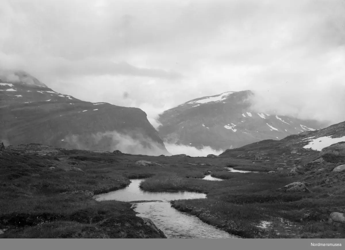Foto av en liten elv høyt oppe i fjellet. Trolig fra Virumdalen i Sunndal kommune etter påskrift på konvolutt. Datering er ikke kjent, men kan trolig være fra tiden omkring 1930 til 1960. Fra Nordmøre museums fotosamlinger.
