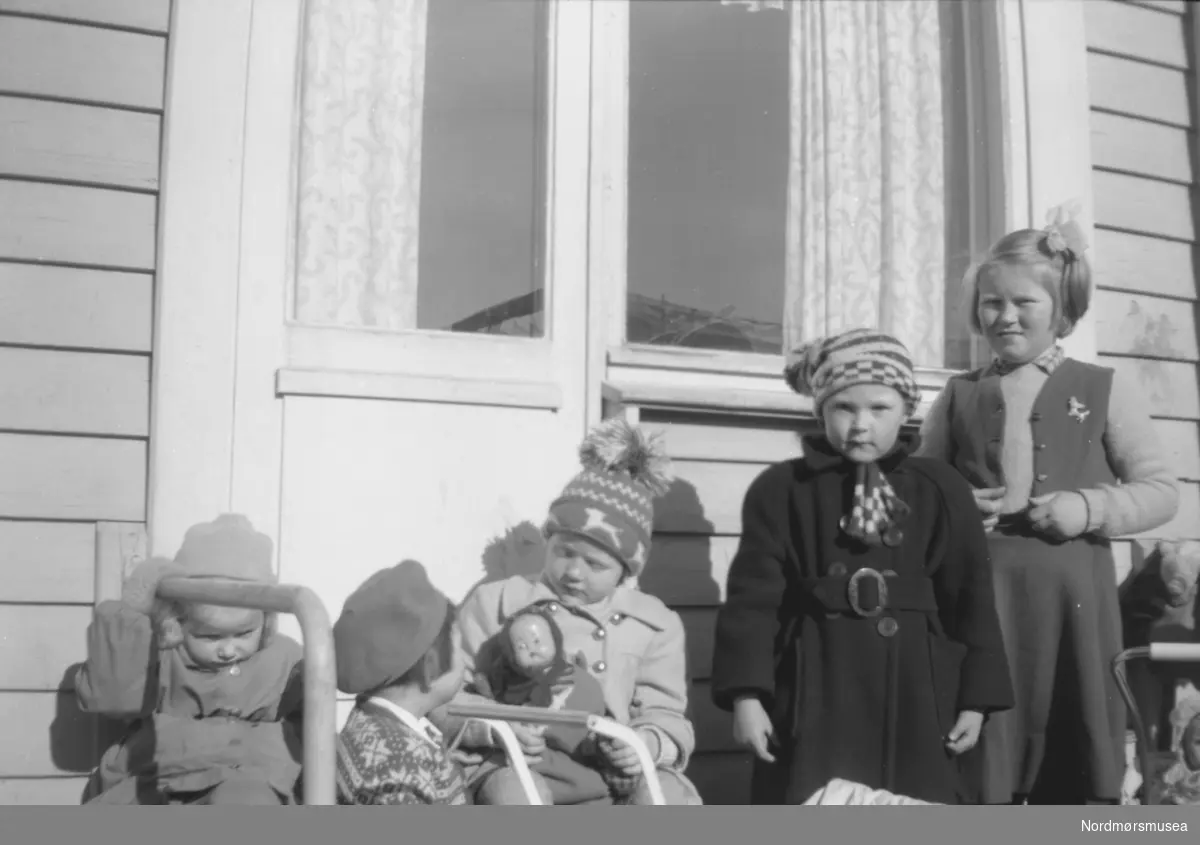 Her ser vi en gruppe barn ute på terassen til en bolighus. Trolig enten familie, slekt eller bekjente av fotografen, som sannsynligvis er John Myhren. Datering er ukjent, men trolig mellom 1930 til 1960. Stedet er også ukjent, men kan være fra Sunndal kommune.
Fra Nordmøre museums fotosamlinger.
