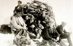 En gruppe menn og kvinner på skitur, her sittende ved en ste