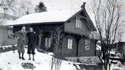 Foto av to menn foran ei hytte en vinterdag. Hytta er mulige