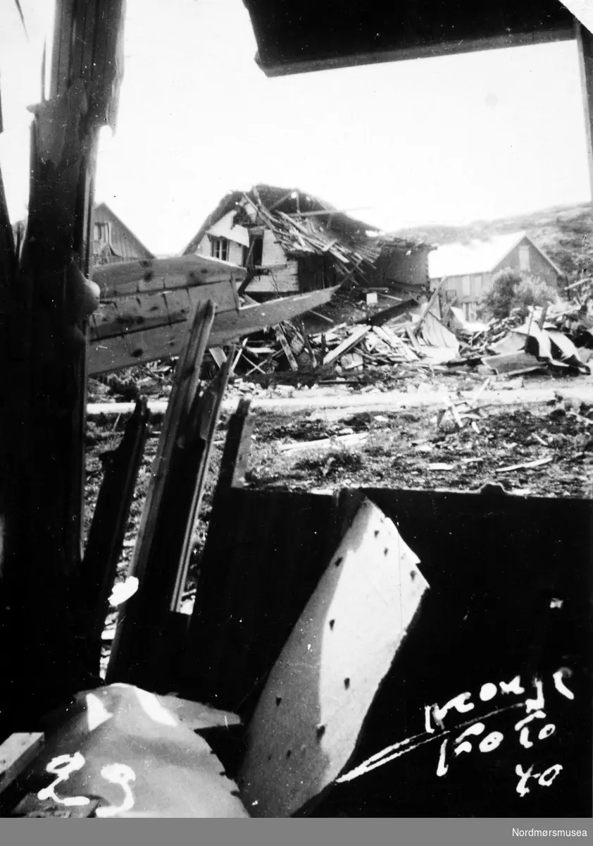 Krigen har kommet til Kristiansund. Etter nazistenes herjinger i perioden 28. april til 1. mai 1940 ligger byen i ruiner. Det totale antall brente bygg var 767, hvor 605 av disse var på Kirkelandet og 162 på andre ";land"; i Kristiansund. Her fantes det til blant annet til sammen 3906 boliger ifølge boligtellingen av 1938, og av disse brant 2162 boliger ned og 7099 mennesker ble husløse. I tillegg til de 767 brente byggene brant 36 brygger (fiske-pakkhus) ned til grunnen, hvorav 34 lå på andre ";land";. Verdien av de brente byggene beløp seg til kroner 26,9 millioner for Kirkelandet (kroneverdi per 1940) eller tilsammen 30,6 millioner kroner (kroneverdi per 1940) for hele byen. Fra Nordmøre Museums fotosamlinger. Kilde: Gjenreisningsproblemer i Kristiansund. Fremlagt ved gjenreisningsinstituttet i Kristiansund. Juli 1945. Side 16 - 20.
 -- Peter Storvik: Ødelagt hus etter sprengbomben på Dahle ved Kristiansund, 28. april 1940. I forgrunnen skimter en tomten og området hvor 4 mennesker ble drept. De drepte var Peder Gaupseth, Kristian Gundersen, moren i Ohrvikhuset Olga Ohrvik og sønnen Asbjørn Ohrvik.                                                                Det ødelagte huset i front tilhørte familien Peder Moen. Til venstre for Moenhuset ses huset til familien Liabø og helt i høyre kant av bildet ses såvidt litt av flerleilighetshuset til familiene   Kristian Gundersen, Johan Fjællingsdal, Johan Johansen og Hjalmar Alstad. Huset til Moen lå på hjørnet mellom Daleveien og veien opp til Persløkka. Daleveien ses som en grå stripe på bildet.   På veien opp til Persløkka er det satt opp en minnetavle med navn på drepte etter bombingen.  Bildet er tatt fra inne i Ingebrigtsens hus og er fra 1940.
