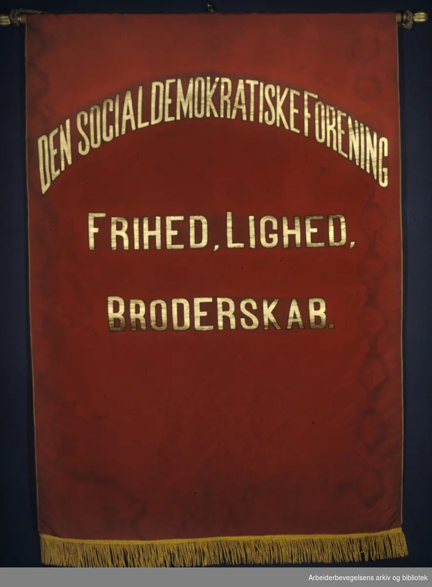Den socialdemokratiske forening.Stiftet i 1885..Forside..Fanetekst: Den socialdemokratiske forening. Frihed, lighed, broderskab....