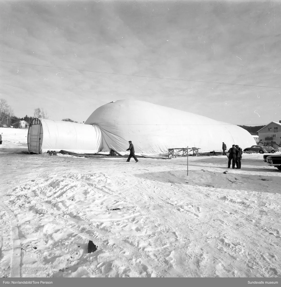 Husbygge i Granlo vid Vikingavägen-Höderbacken. Ett stort tält är uppställt och innanför tältväggarna pågår markarbetena för fullt.