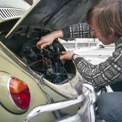 Mann arbeider i motor på folkevogn