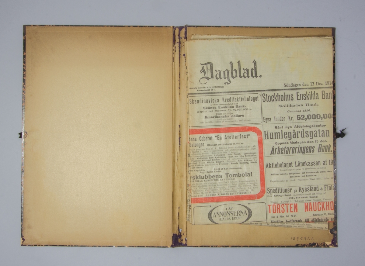 Portfölj av marmorerad papp. Sammanhållen med knytband. Rygg av lila linne. Innehåller enbart flera exemplar av Stockholms Dagblad från 1914.