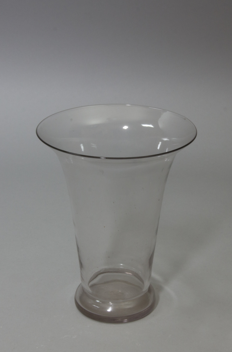 Blomglas i bägarform med utvikt mynning. Klart glas.