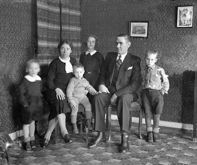 Foto av en familj med två små pojkar och en flicka. De är samlade i ett vardagsrum.