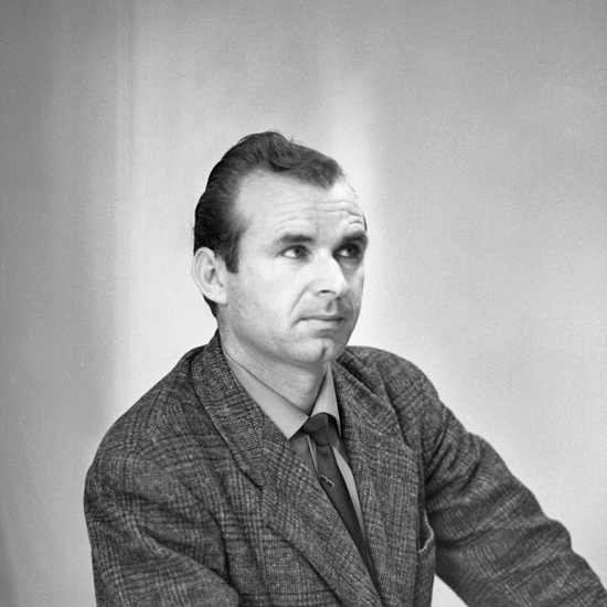 Foto av en okänd man i tweedkavaj och slips.
Bröstbild, halvprofil. Ateljéfoto.