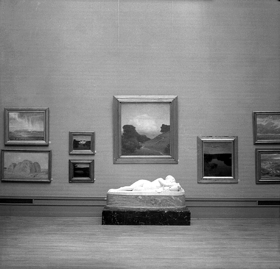 Prins Eugens utställning.
På väggen hänger flera tavlor, bl a "Molnet" och på golvet framför syns 
en stor liggande marmorskulptur.