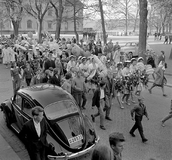 Studenterna, tredje d. 1960. 
Studenterna m.fl. tågar längs Skolgatan, mot Linnéparken och 
talet vid Esaias Tegnérs staty. I bakgrunden syns Norrtullskolan.