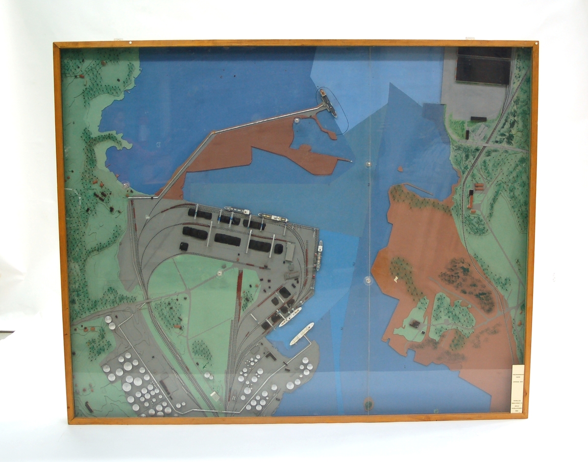 Acc. kat: Stadsbyggnadsmodell, föreställande Fredriksskans hamn utanför Gävle. Tillverkad i trä och täckt med plexiglas. Skylt i nedre högra hörnet: "Fredriksskans hamn omkring 1970. Modellen renoverad av Gävle Modellbyggeri 1992."
