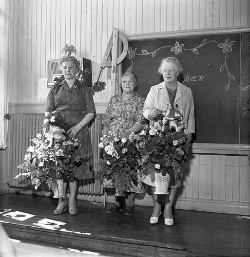 Sista skoldagen med avtackning i Reaby skola 1962. Lärarinnorna Anna-Lisa Lundin och Ruth Pettersson flankerar städerskan Edit Svahn. Alla med blomsterbuketter i famnen.